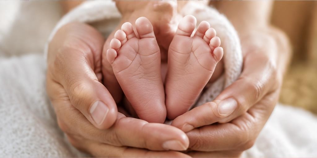 Newborn feet resting gently in adult hands